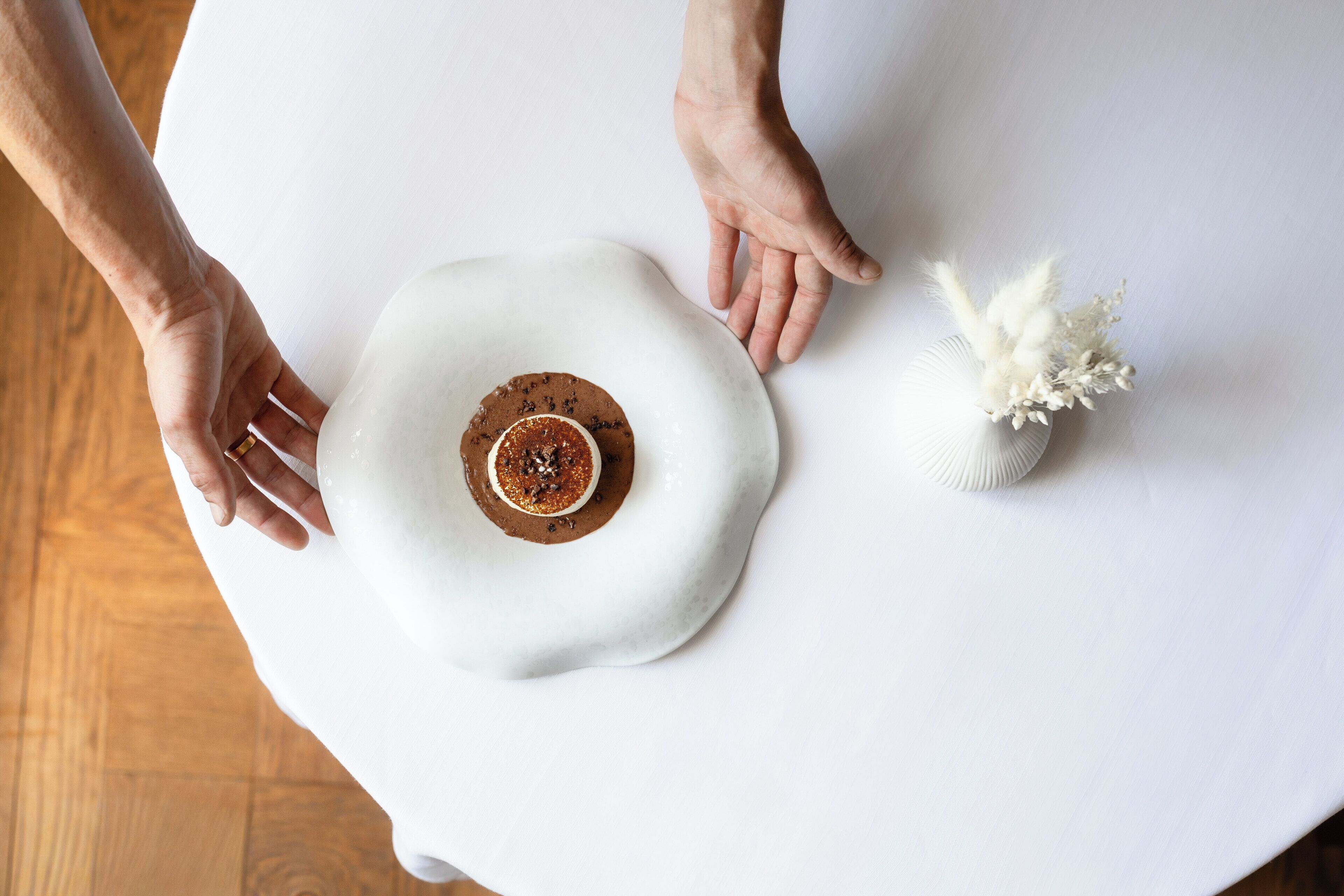 Un tavolo bianco con un oggetto centrale e un piccolo vaso bianco con fiori bianchi.