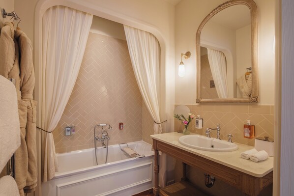 Un baño con bañera, lavamanos, espejo y toallas.