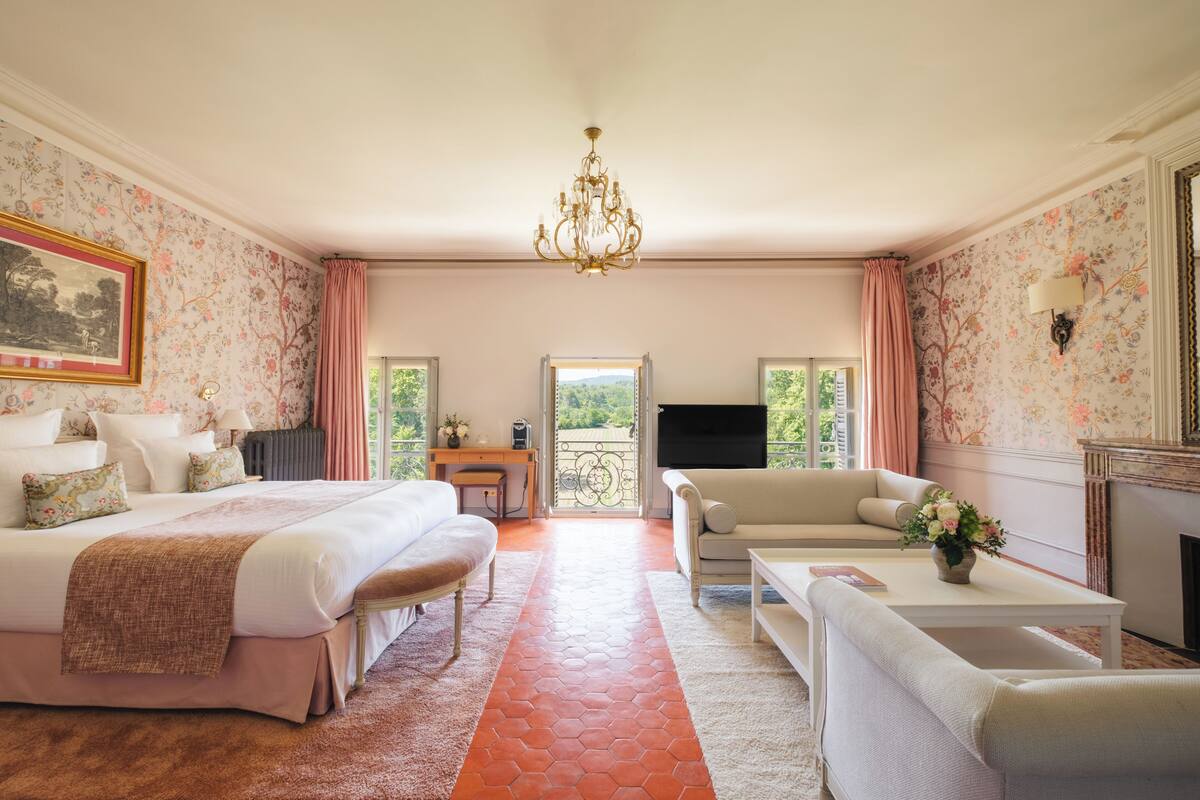 A bedroom with a large bed, a sofa, a coffee table, and a fireplace.