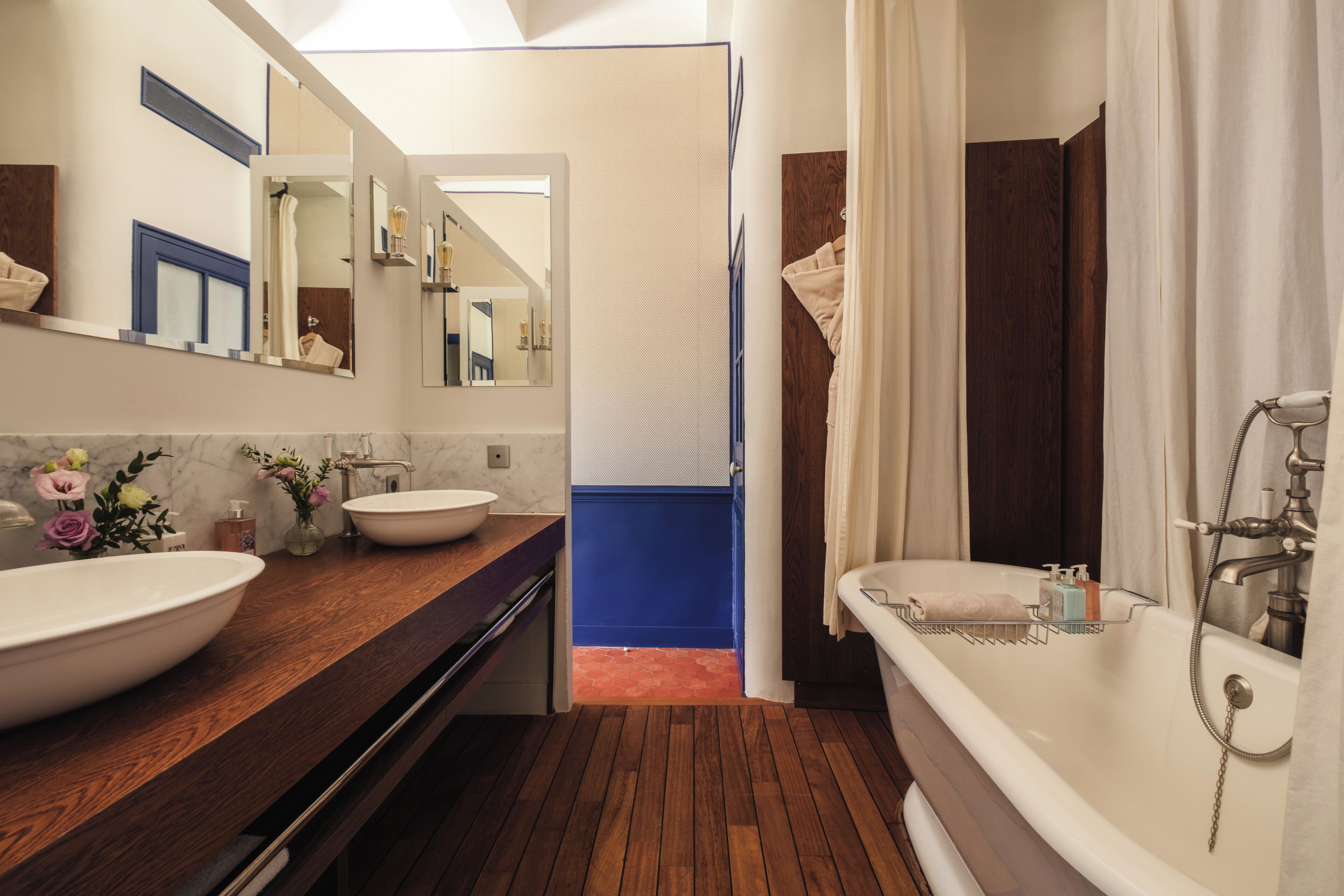 Un baño con tocador de madera, un lavabo grande blanco, una bañera y un espejo.