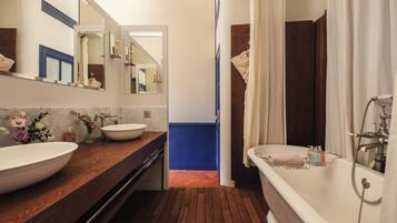 Un baño con tocador de madera, un lavabo grande blanco, una bañera y un espejo.
