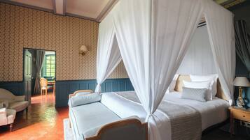 A four-poster bed with white bedding, a wooden headboard, and a nightstand with a lamp.