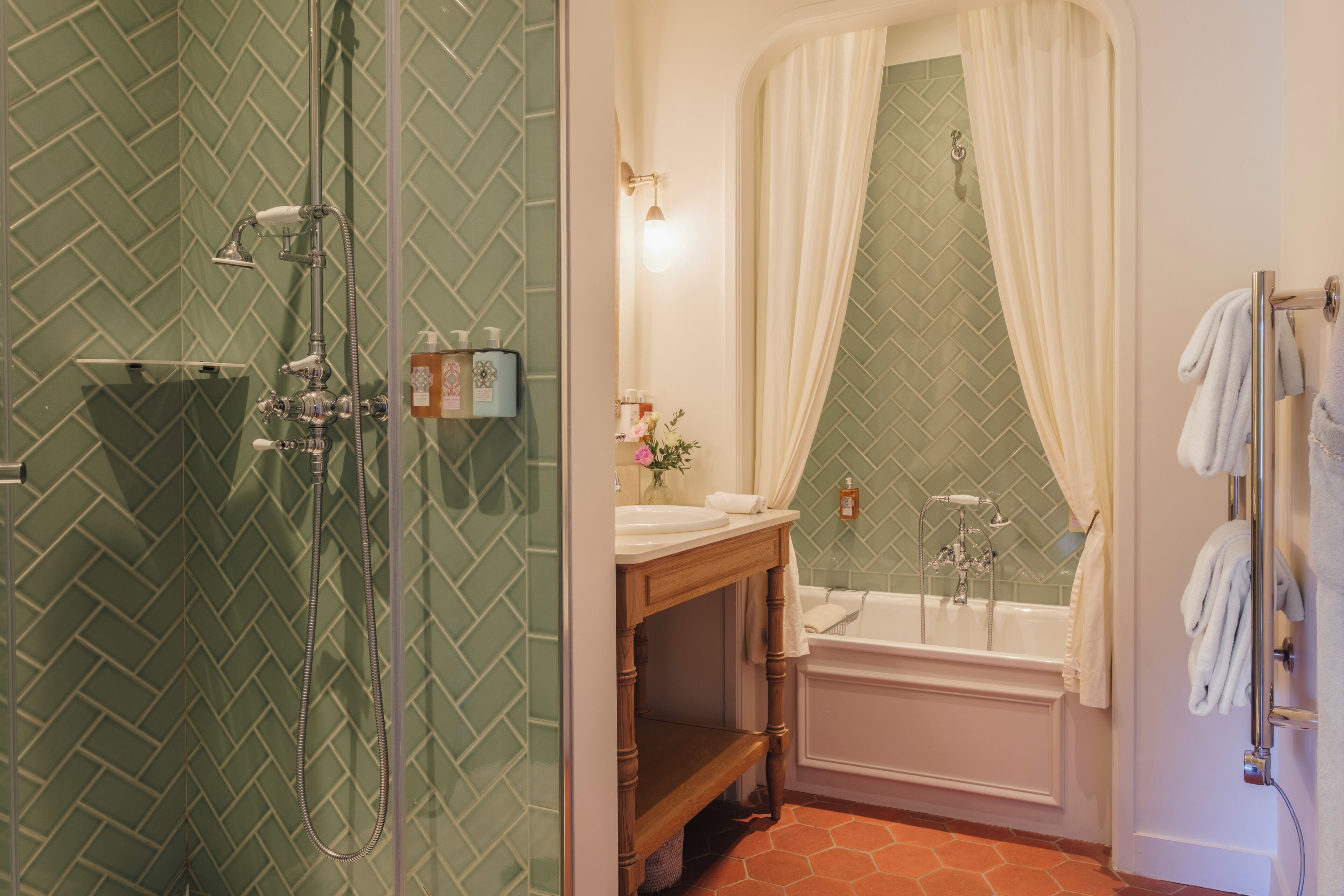 A bathroom with a shower, sink, and bathtub, featuring green patterned walls and a wooden vanity.