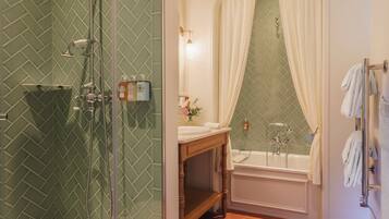 A bathroom with a shower, sink, and bathtub, featuring green patterned walls and a wooden vanity.
