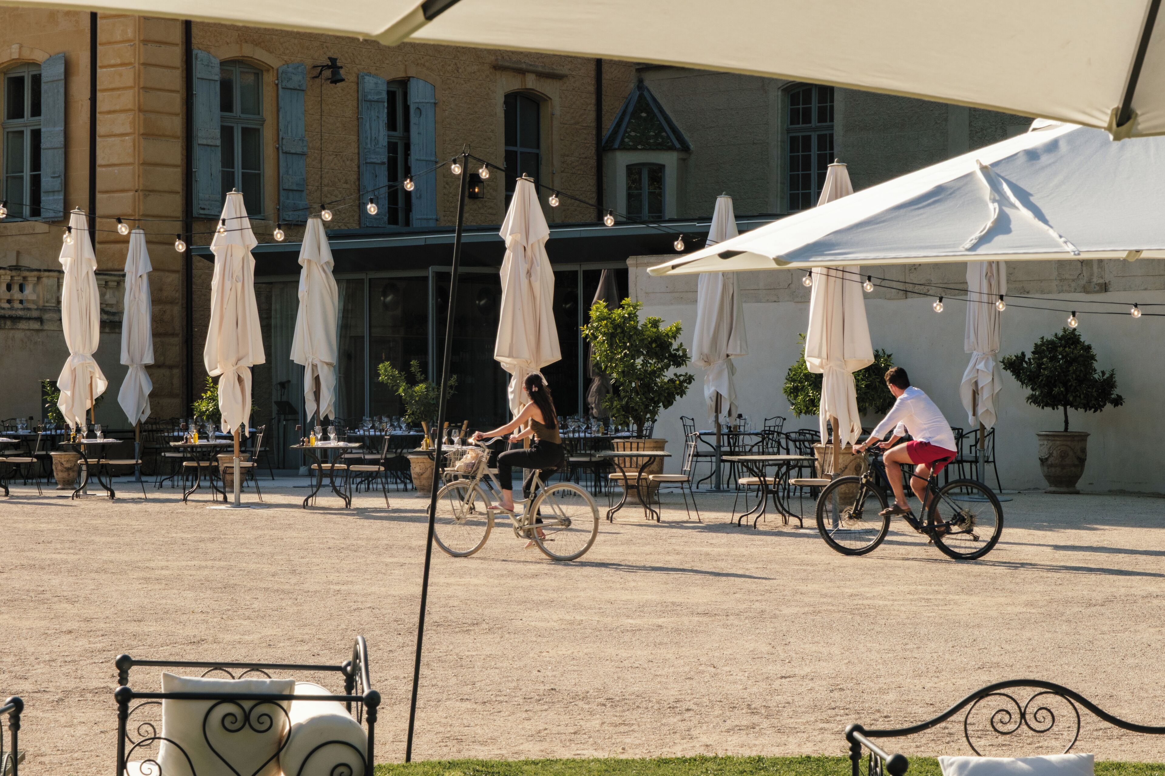 An outdoor café with tables and chairs, bicycles, and umbrellas.