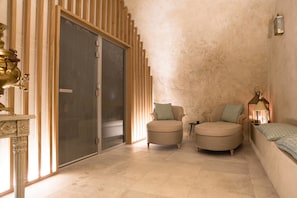 A room with a sliding door, two armchairs, a sofa, a small table, and a decorative lamp.
