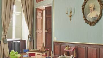 Cozy retreat with a traditional fireplace, comfortable seating, and a charming painting.