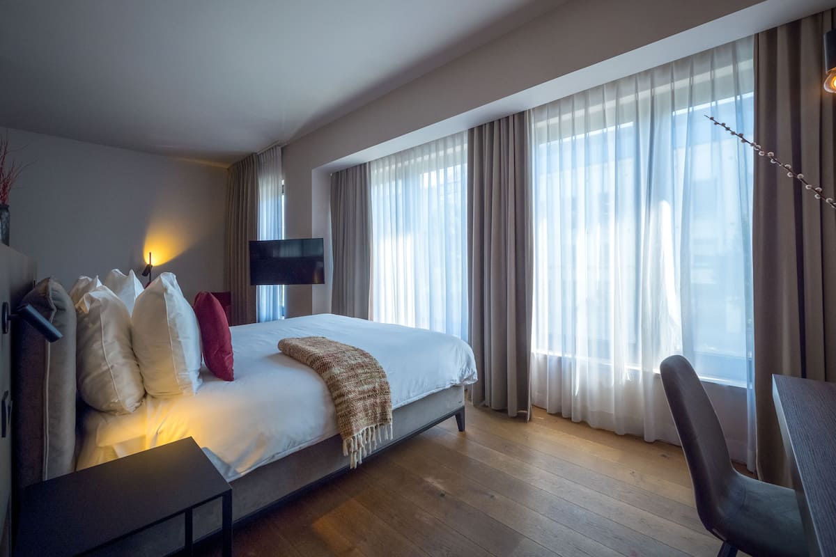 A modern hotel room with a large bed, a flat-screen TV, a desk, and a chair.