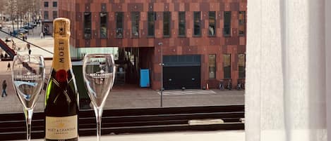 A bottle of Moët & Chandon champagne and two glasses on a table with a view of a modern building with a brick facade and large windows.
