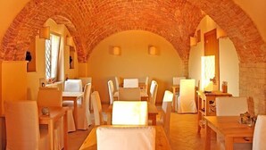 A dining area with brick arches, white furniture, and warm lighting. - The Olive Inn (Lesina)