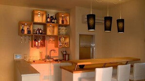 A modern kitchen with a central island, wooden shelves with bottles, and hanging pendant lights. - The Olive Inn (Lesina)
