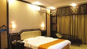 A hotel room with a bed, bedside table, and a chair. - Nantian Hotel (Liuzhou)