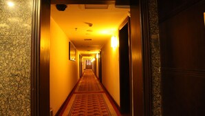 A hotel hallway with a carpeted floor, wooden doors, and a light fixture on the wall. - Nantian Hotel (Liuzhou)