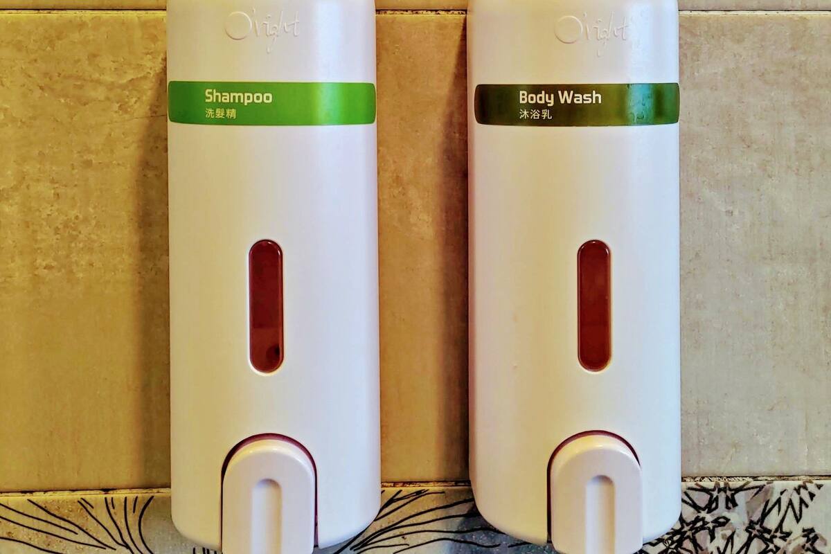 Two bottles of Olay products, one labeled 'Shampoo' and the other 'Body Wash', placed on a patterned surface.