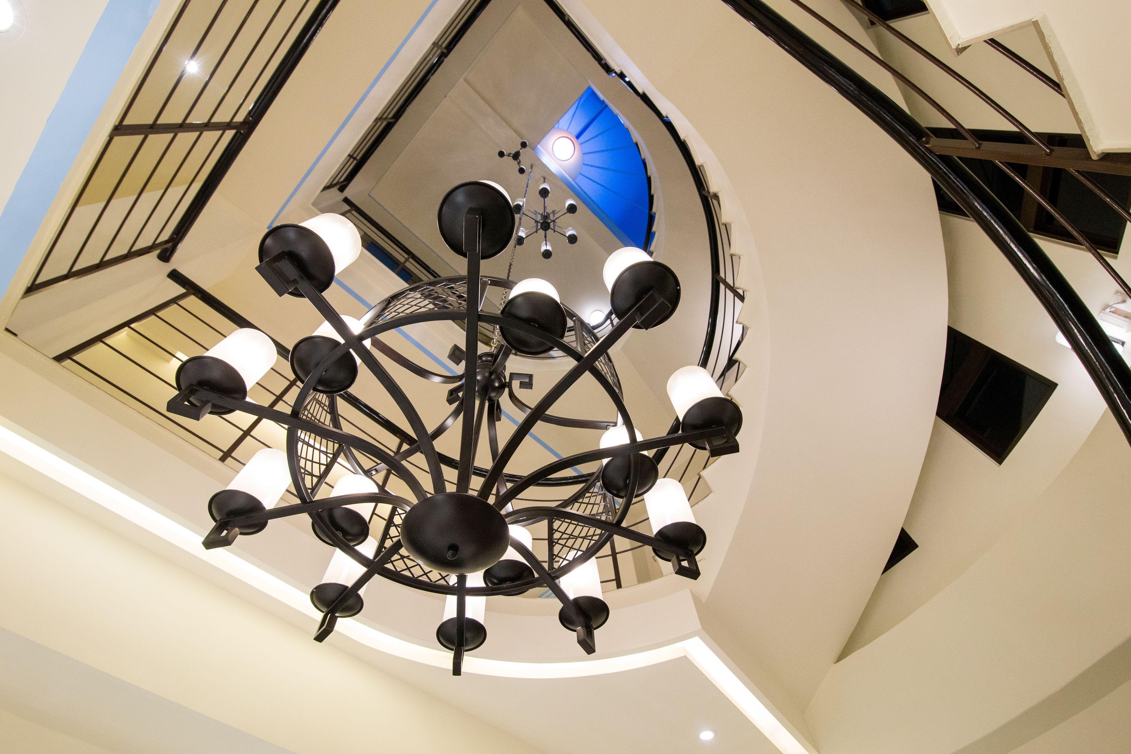 A modern chandelier with multiple arms and hanging lights in a spacious atrium.