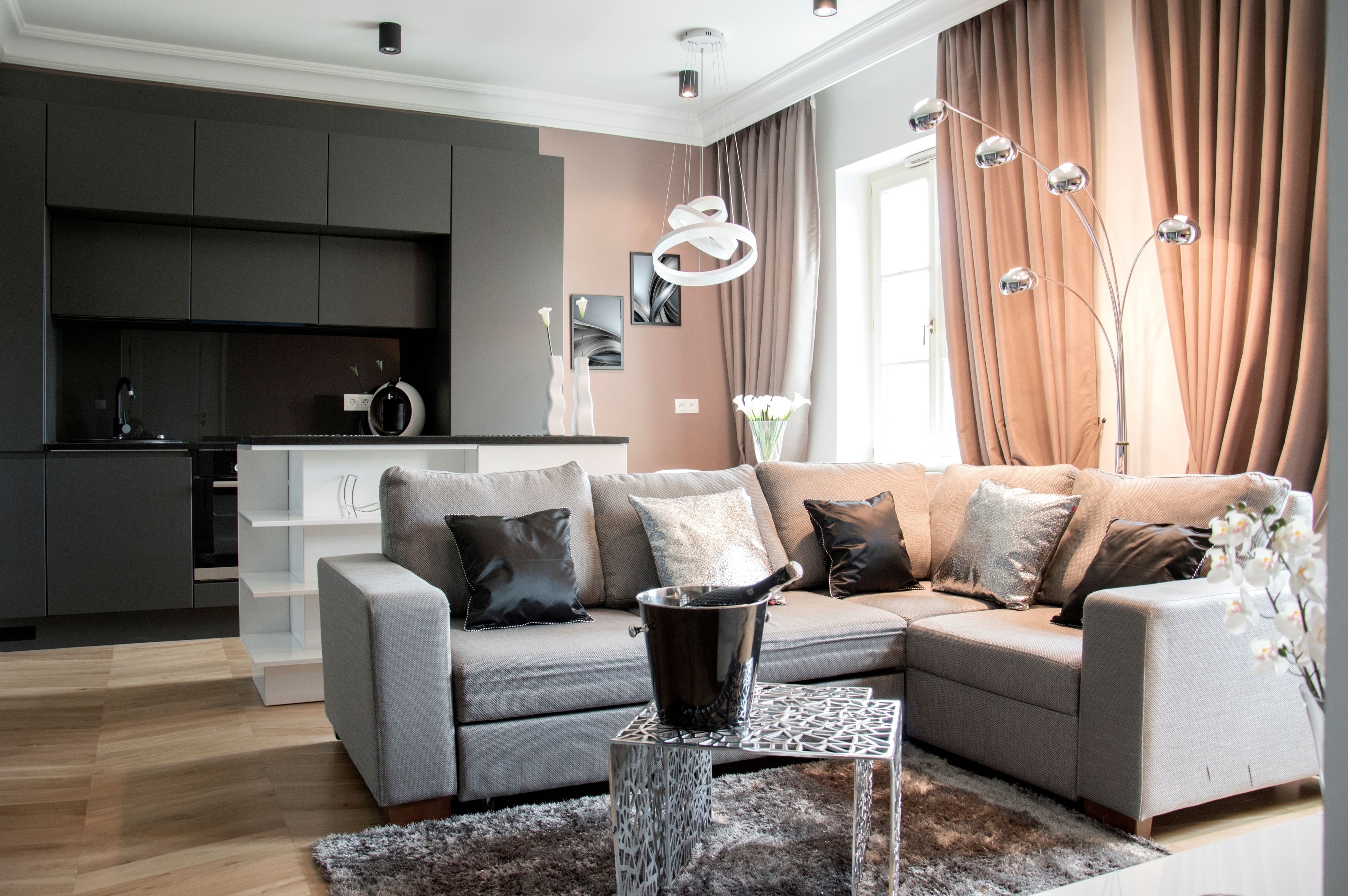 A modern living room with a grey sofa, a coffee table, and a kitchen area in the background.