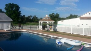 A swimming pool with a gazebo, a fenced area, and a building in the background. - Crystal Run Suites of Springboro (Springboro)