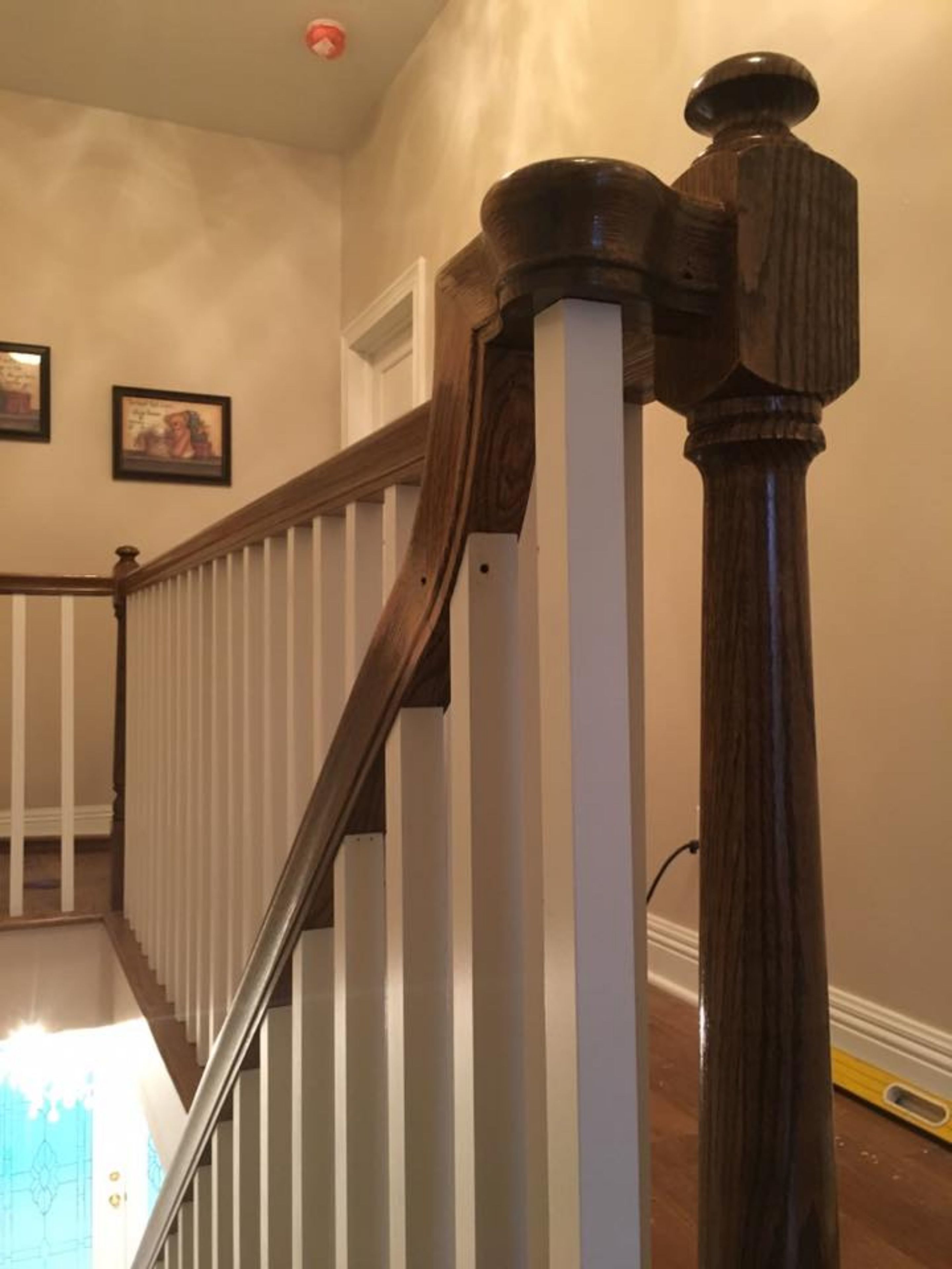 A wooden staircase with a white handrail and a dark wooden balustrade.