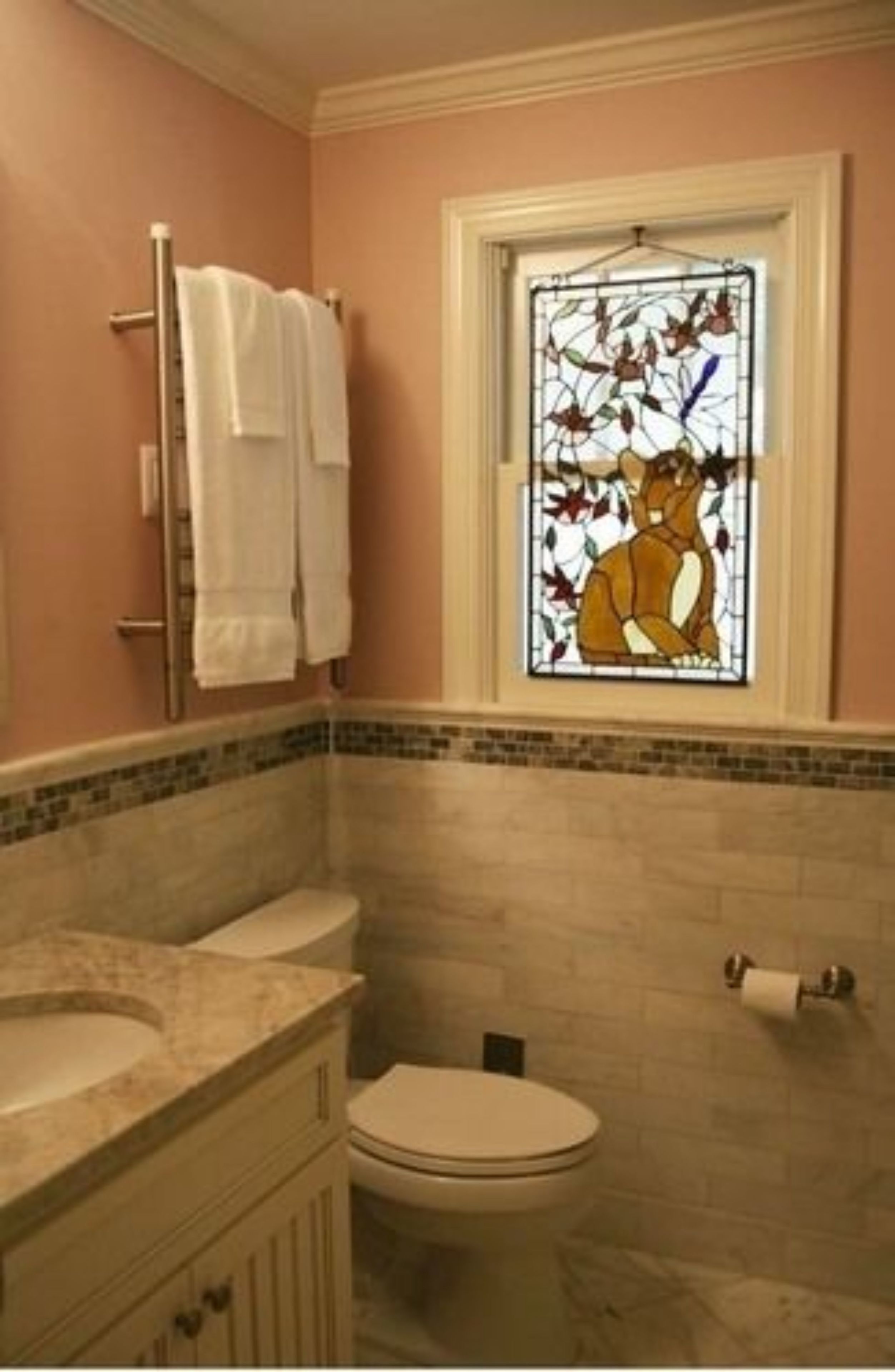 A bathroom with a toilet, a sink, a towel rack, and a stained glass window.