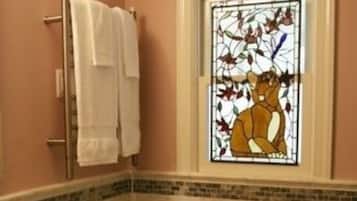A bathroom with a toilet, a sink, a towel rack, and a stained glass window.