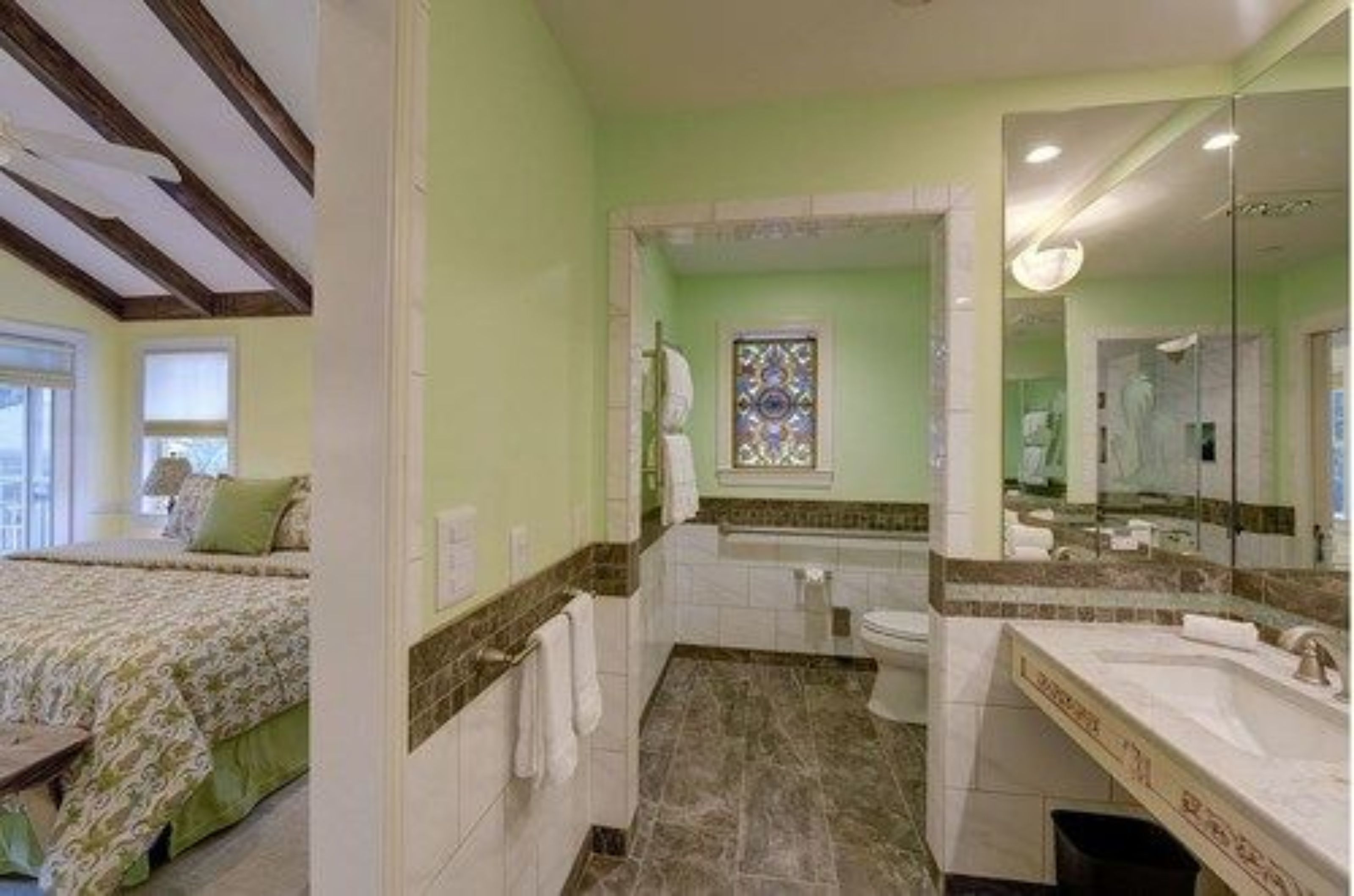Een slaapkamer met een bed, een badkamer met een bad en een grote spiegel.