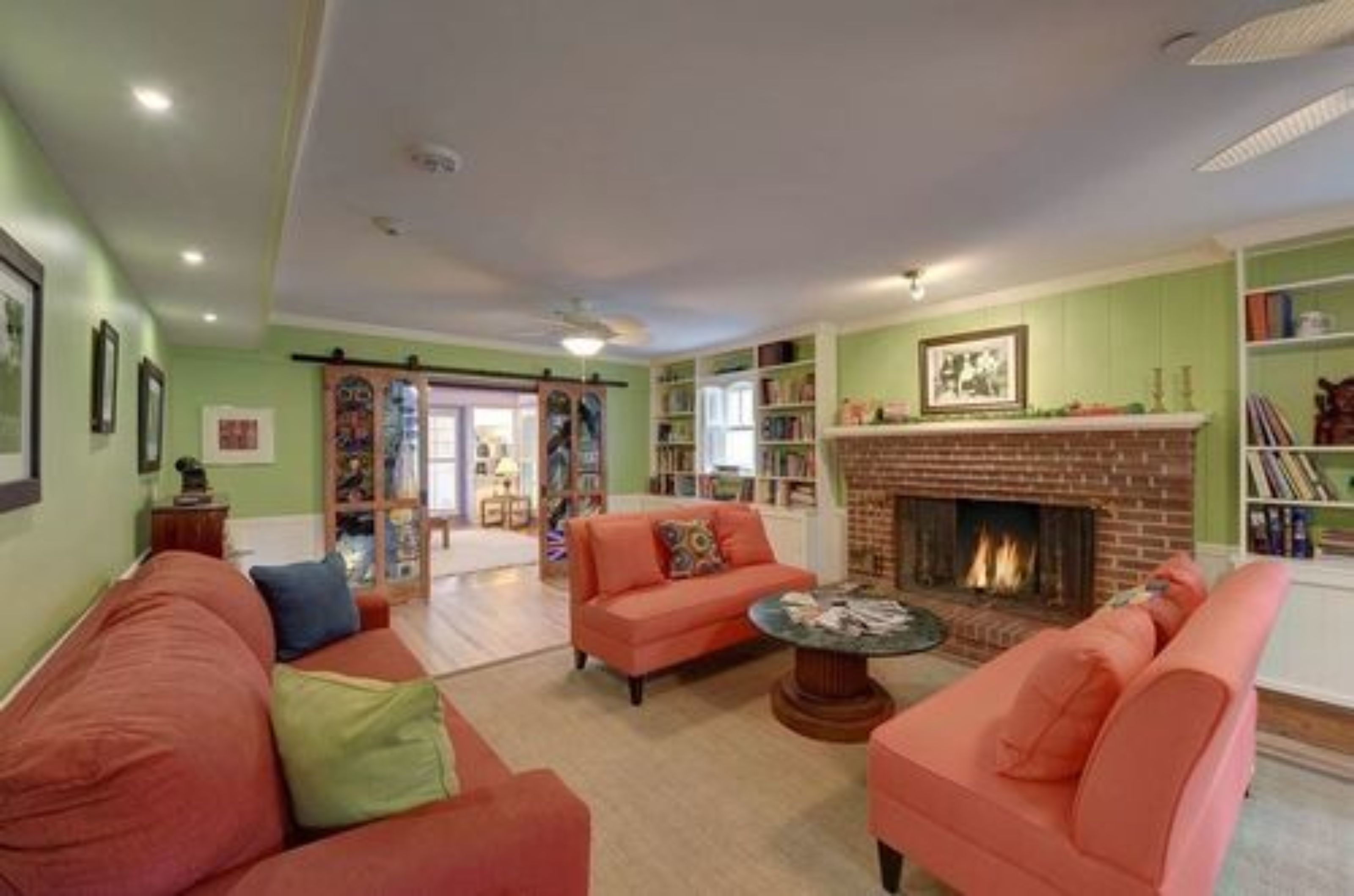 Una sala de estar con chimenea, un conjunto de sofá y una estantería.