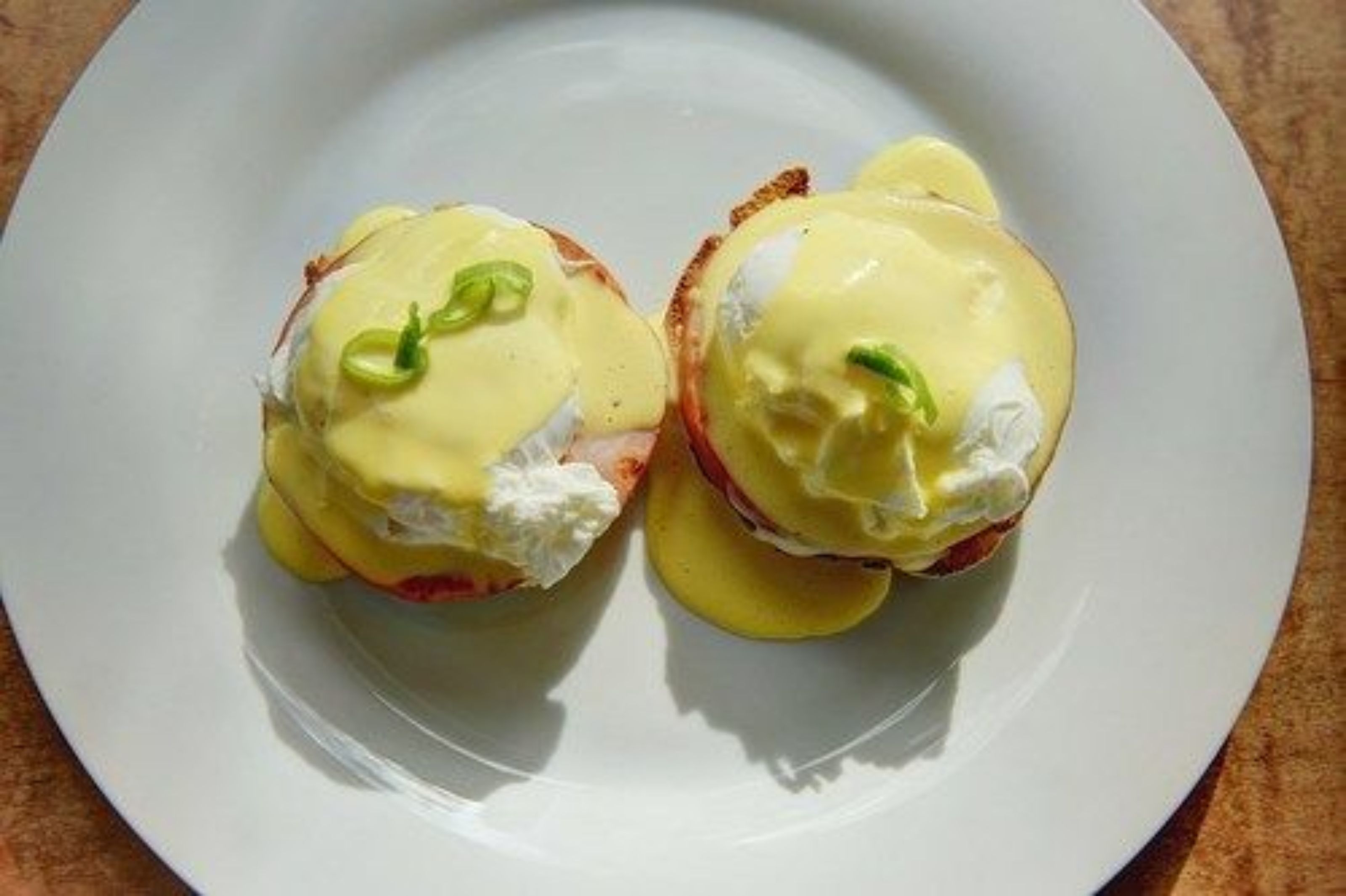 Dos platos de huevos benedictinos sobre un plato blanco.