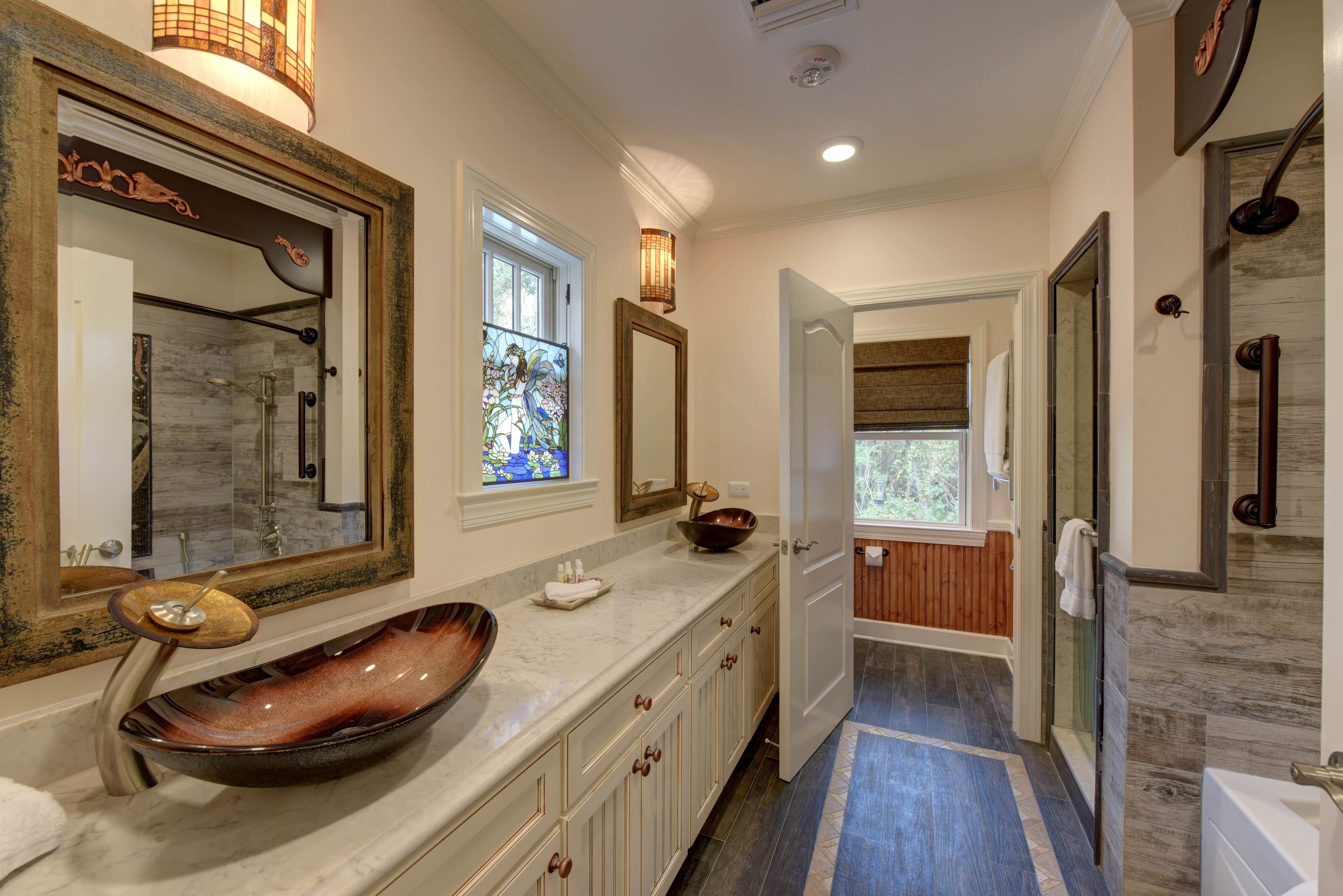 A modern bathroom with a large mirror, a vessel sink, and a walk-in shower.