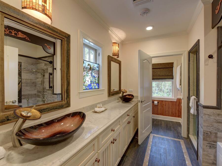 A modern bathroom with a large mirror, a vessel sink, and a walk-in shower.
