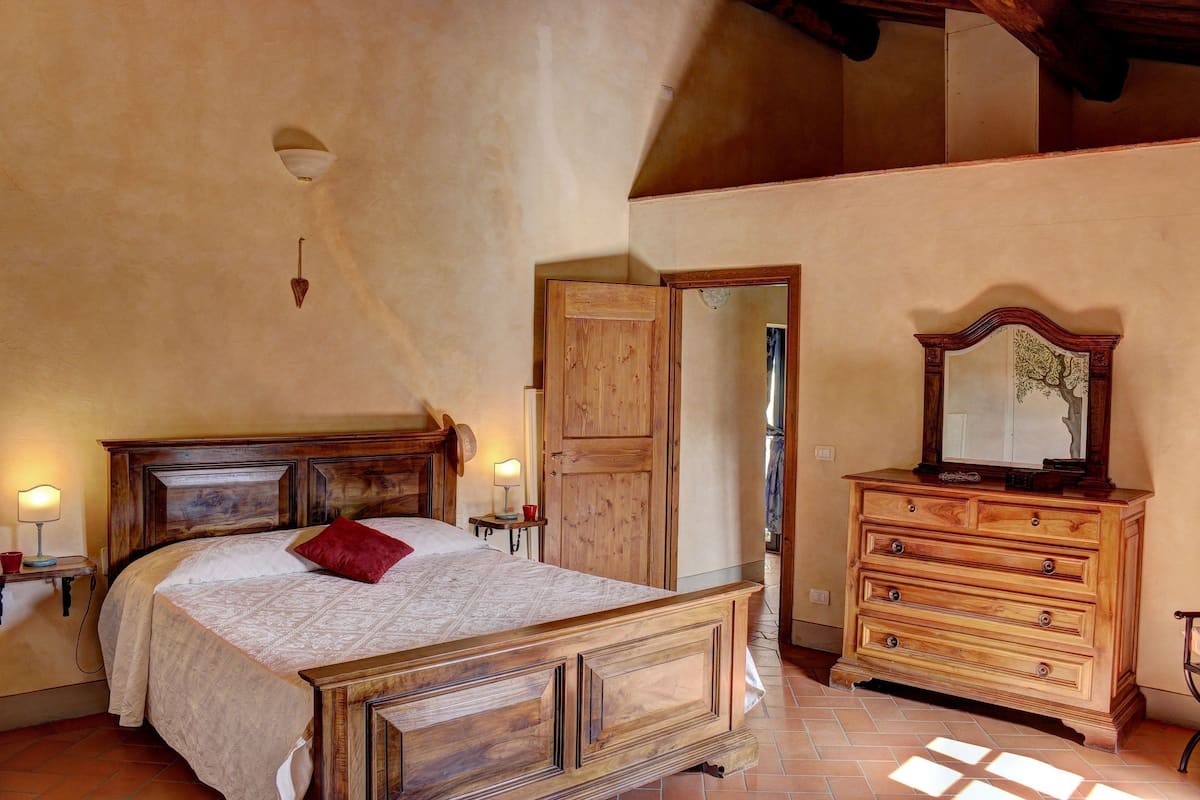 Ein Schlafzimmer mit einem hölzernen Bett, einem Schminktisch und einem Spiegel.