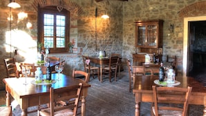 Un comedor rústico con mesas y sillas de madera, paredes de piedra y una chimenea de ladrillo.
