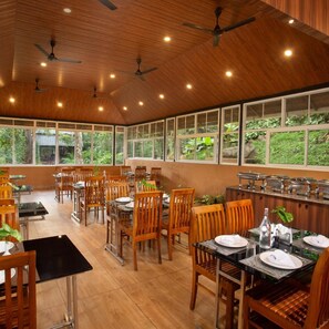 A restaurant with wooden ceiling fans, large windows, and a buffet setup. - Bamboo Dale (Udumbanchola)