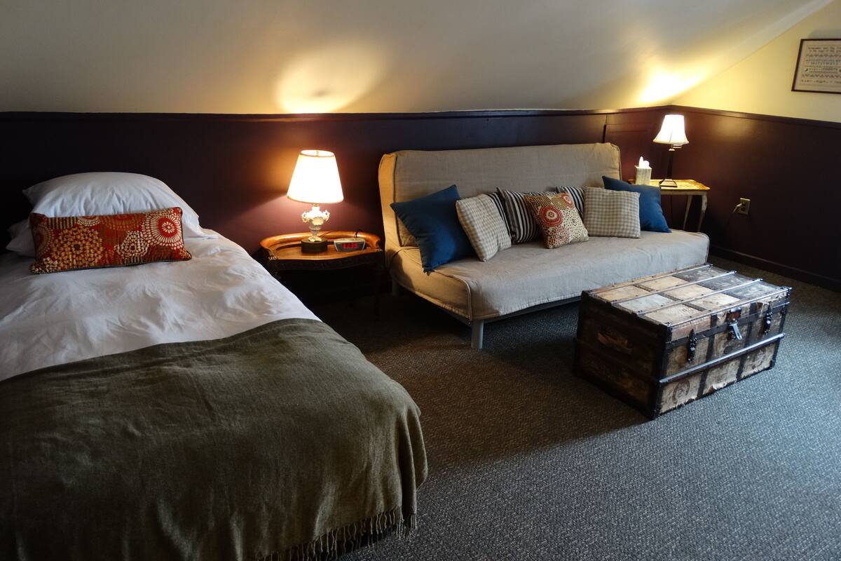 A cozy hotel room with two beds, a sofa, and a small table.