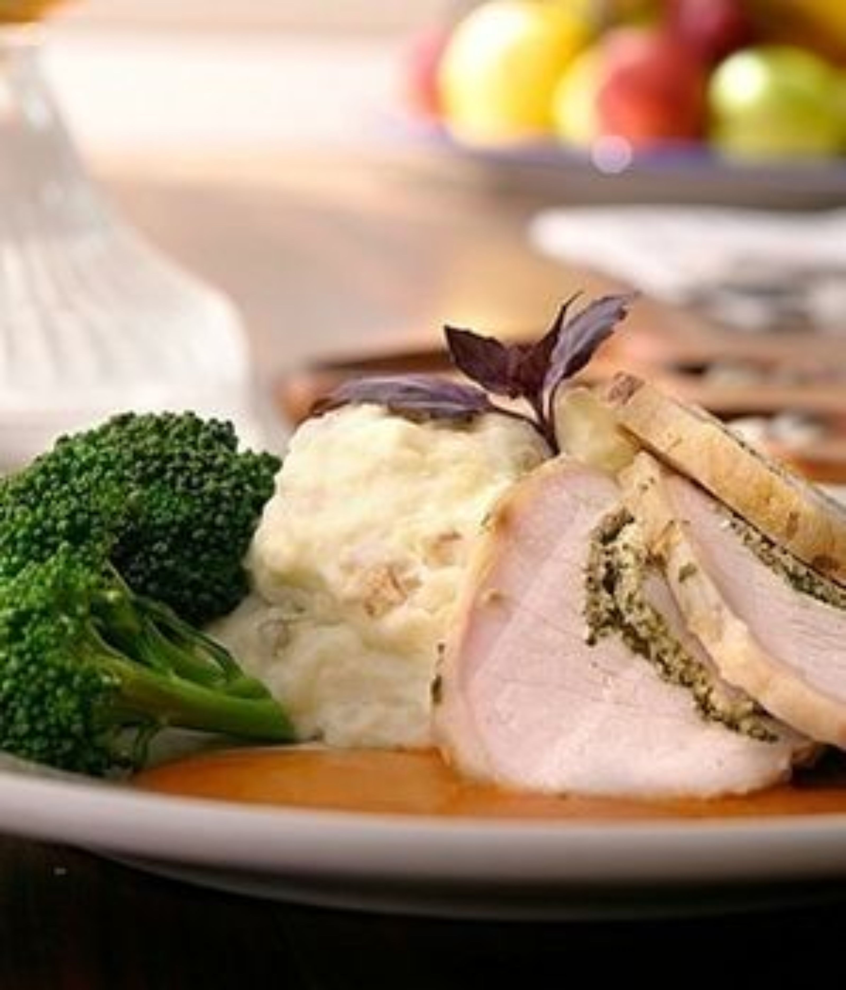 A plate with sliced meat, mashed potatoes, and broccoli.