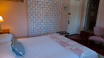 Une chambre à coucher avec un lit, des oreillers, une couette, une chaise et une porte.
