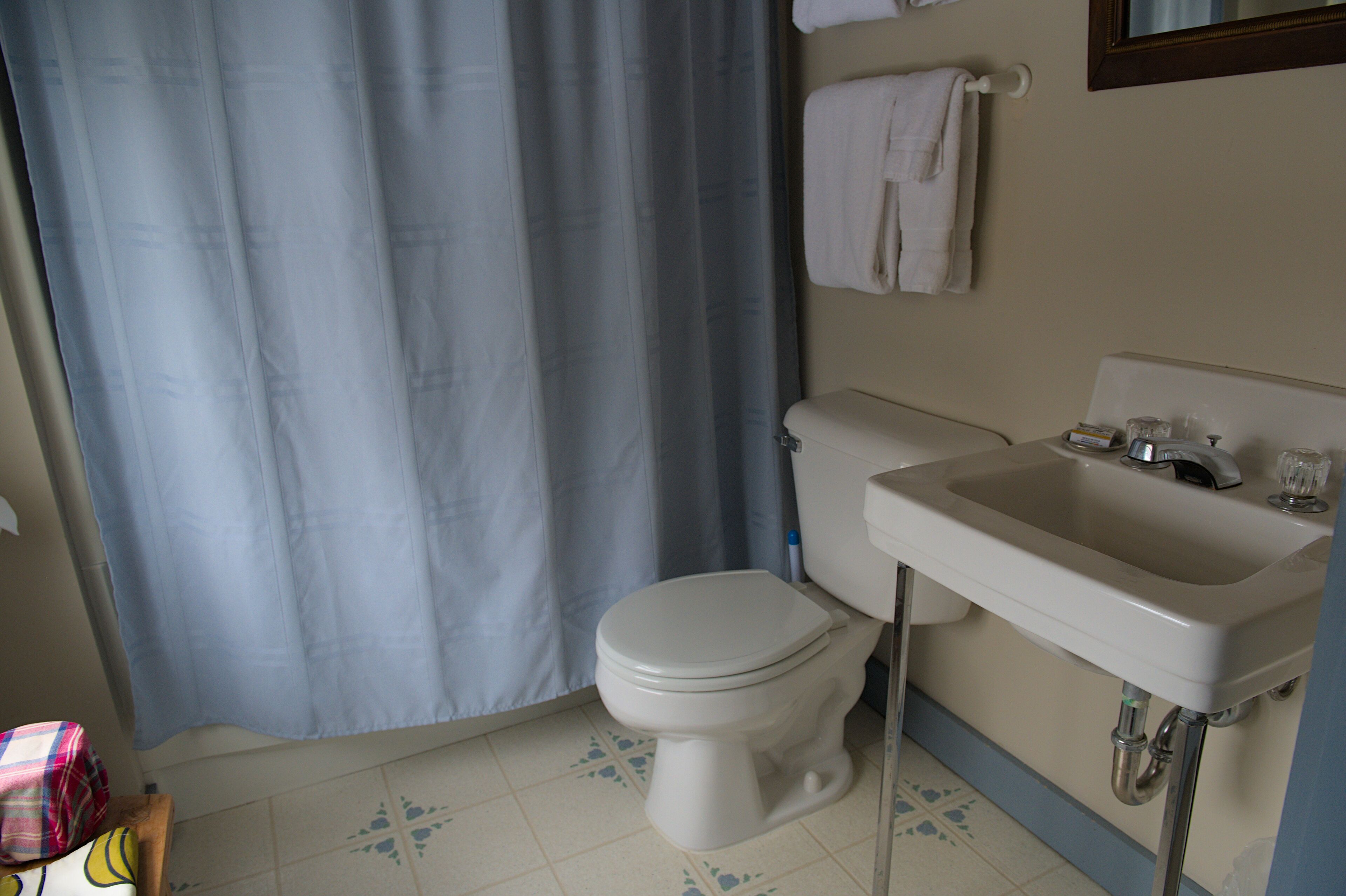 A bathroom with a toilet, sink, and blue shower curtain.