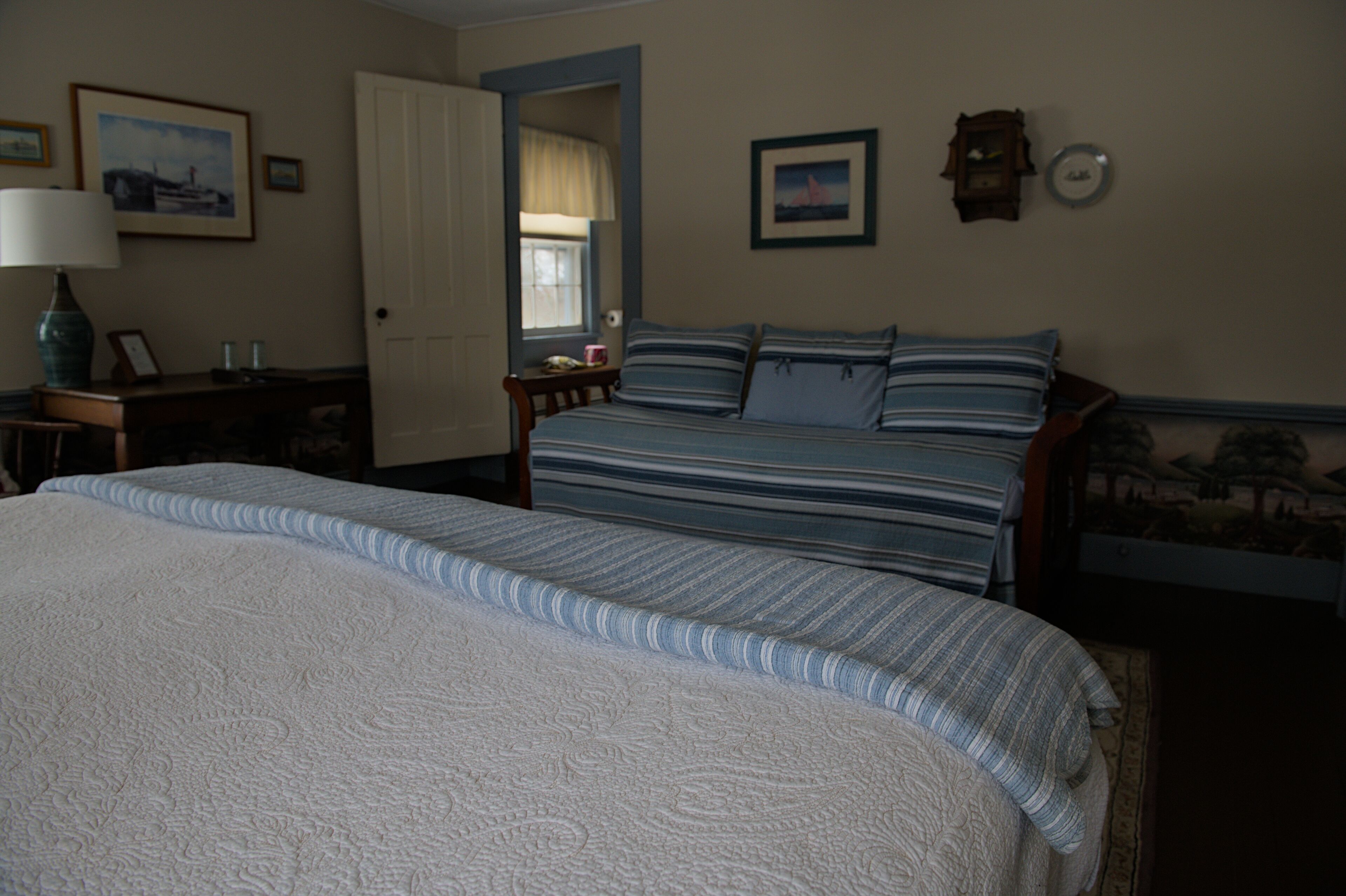 A bedroom with a large bed, a smaller bed, a nightstand, a lamp, and a window.