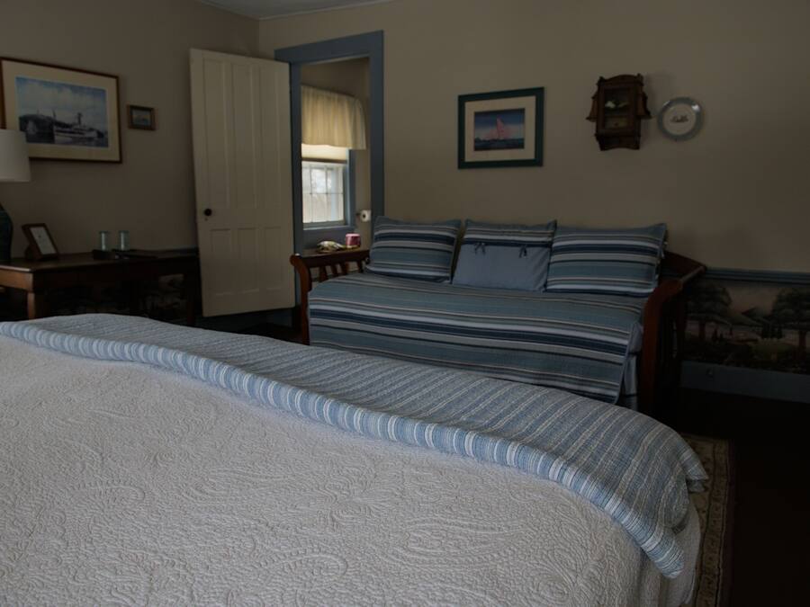 A bedroom with a large bed, a smaller bed, a nightstand, a lamp, and a window.