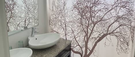 A bathroom with two sinks, a mirror, and a shower curtain with a tree design.