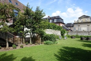 Une cour avec une pelouse verdoyante, un escalier en bois et un mur de pierre.