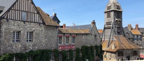 Un edificio histórico con muros de piedra, una torre del reloj y varios letreros que señalan que alberga restaurantes y un hotel.
