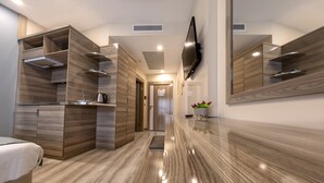 Una habitación de hotel moderna con un armario de madera, un televisor de pantalla plana y un piso pulido.