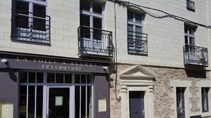 A restaurant named "LA TOILEA A BEURRE" with a stone facade, a dark entrance door, and a balcony with wrought iron railings. - L'hôtellerie de La toile à beurre (Ancenis-Saint-Géréon)