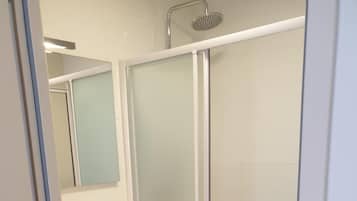 A modern bathroom with a glass-enclosed shower, a sink with a mirror, and a vanity with drawers.