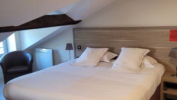 Quarto com cama grande, cabeceira de madeira, uma cadeira, mesa de cabeceira e abajur.
