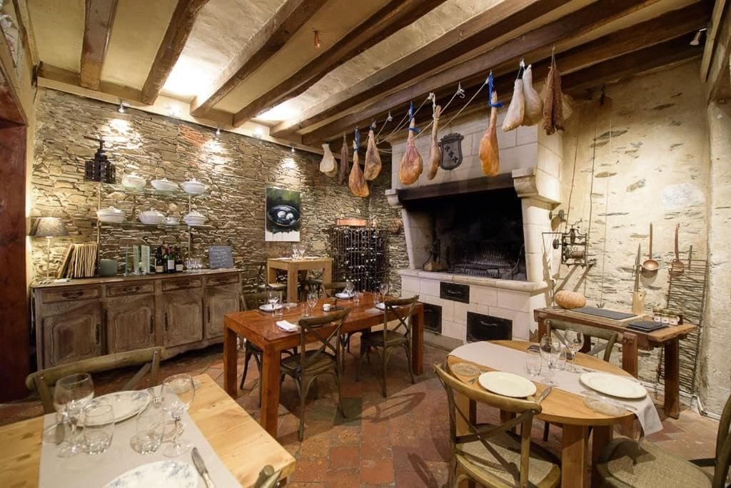 A rustic dining area with stone walls, wooden beams, and a stone fireplace.