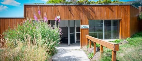 A wooden building with a sign reading 'Restaurant Les Aliziers' and a pathway leading to the entrance.