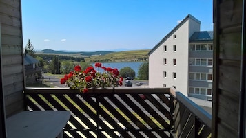A balcony with a view of a lake, buildings, and a clear sky.