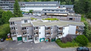 Ett hotell med flera våningar, balkonger, en parkeringsplats och en restaurang på taket.