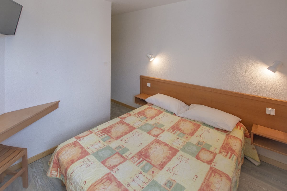 Une chambre à coucher avec un lit, une table de chevet en bois, un bureau et une chaise.